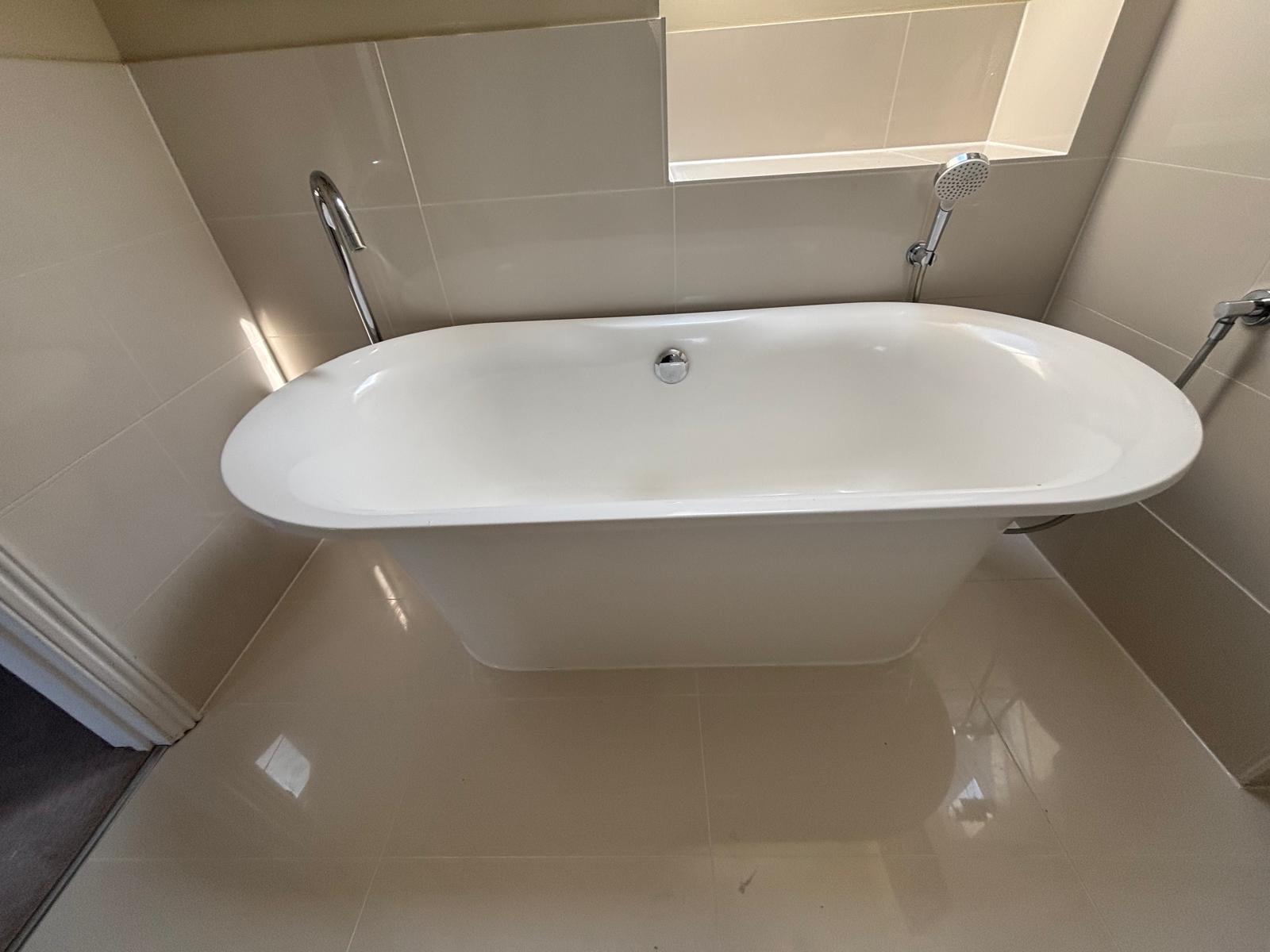 Bathroom reseal — freestanding bath with chrome fittings and large format tiles