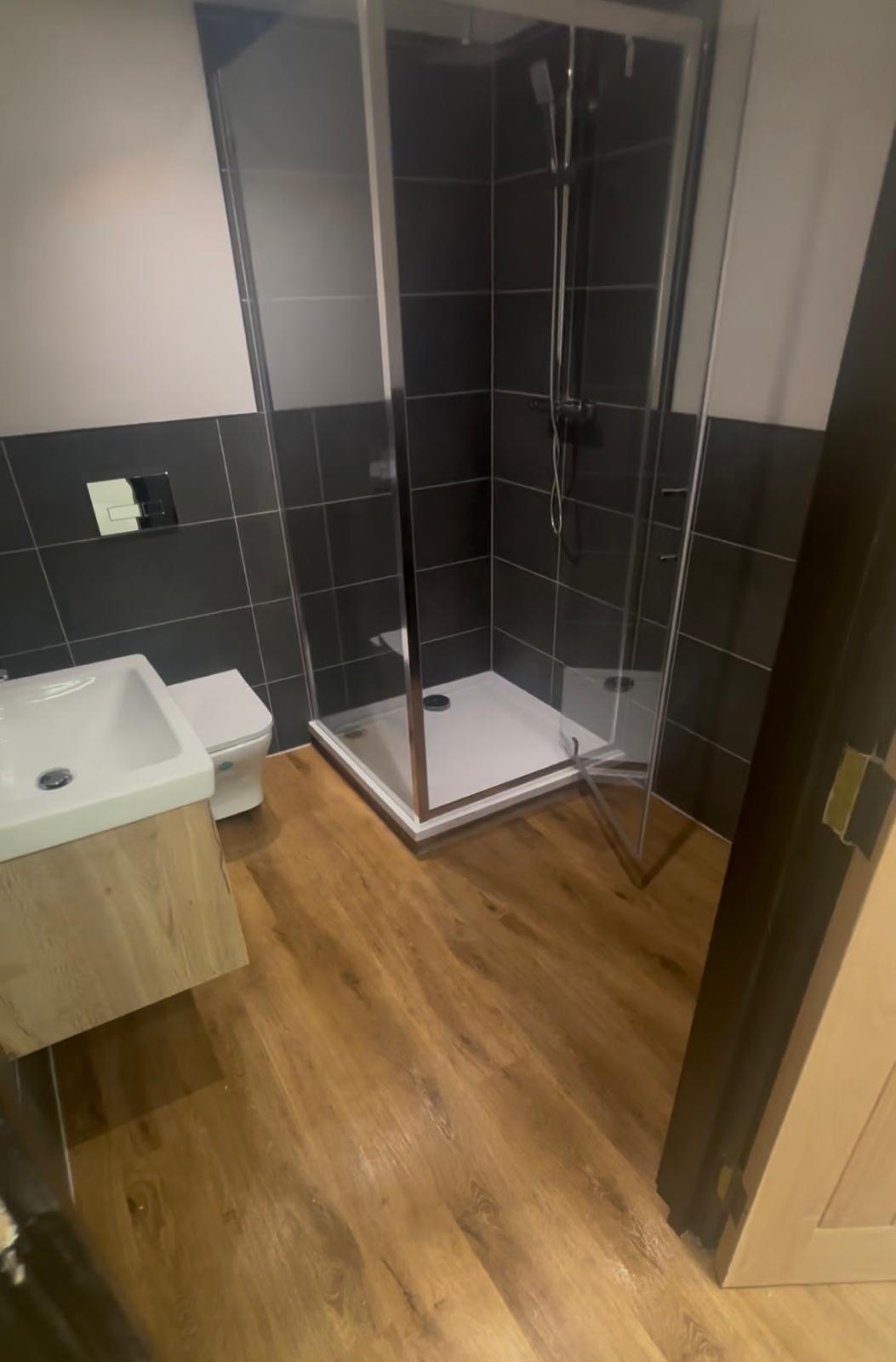 Forever Padel — completed shower room with dark tiles and glass enclosure