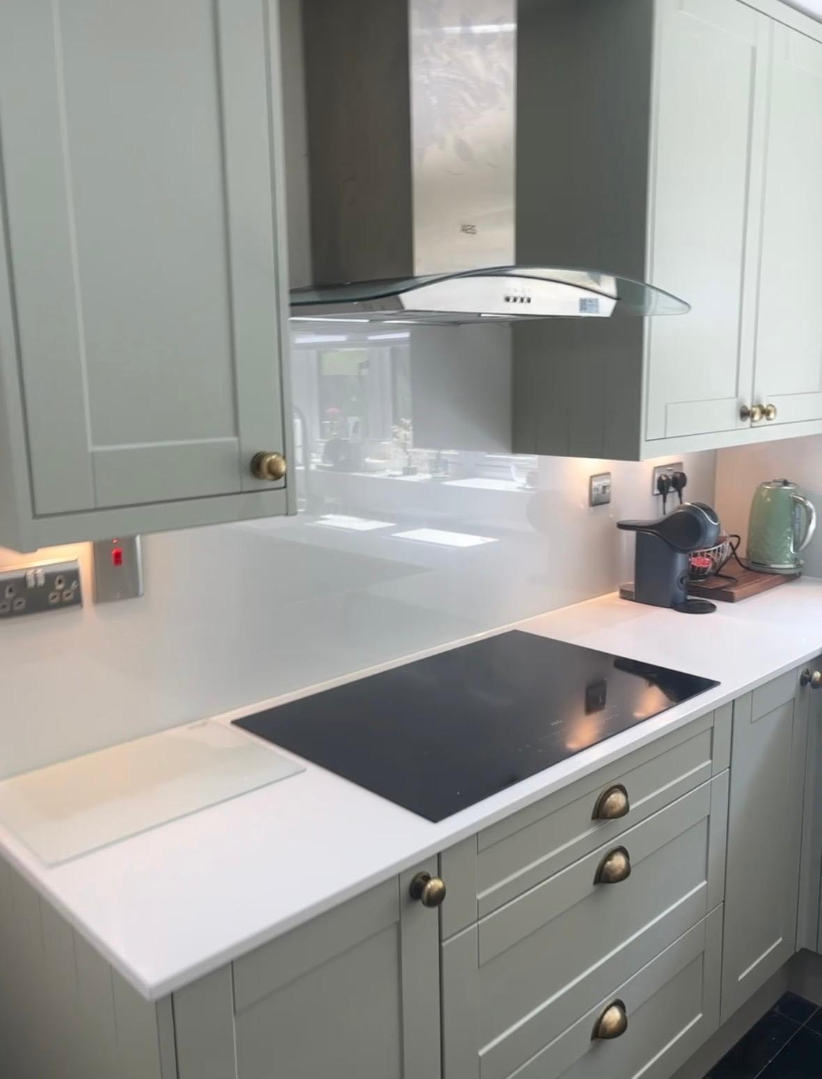 Sage green kitchen with glass splashback and white quartz worktop — silicone sealed