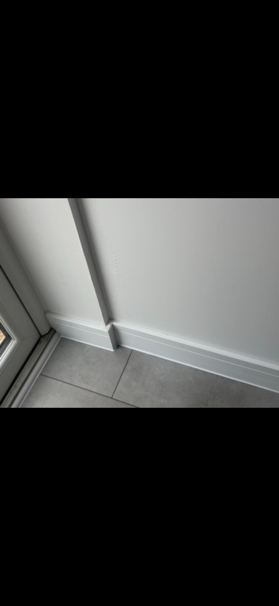 LVT floor edge sealing — grey tile meeting white skirting board