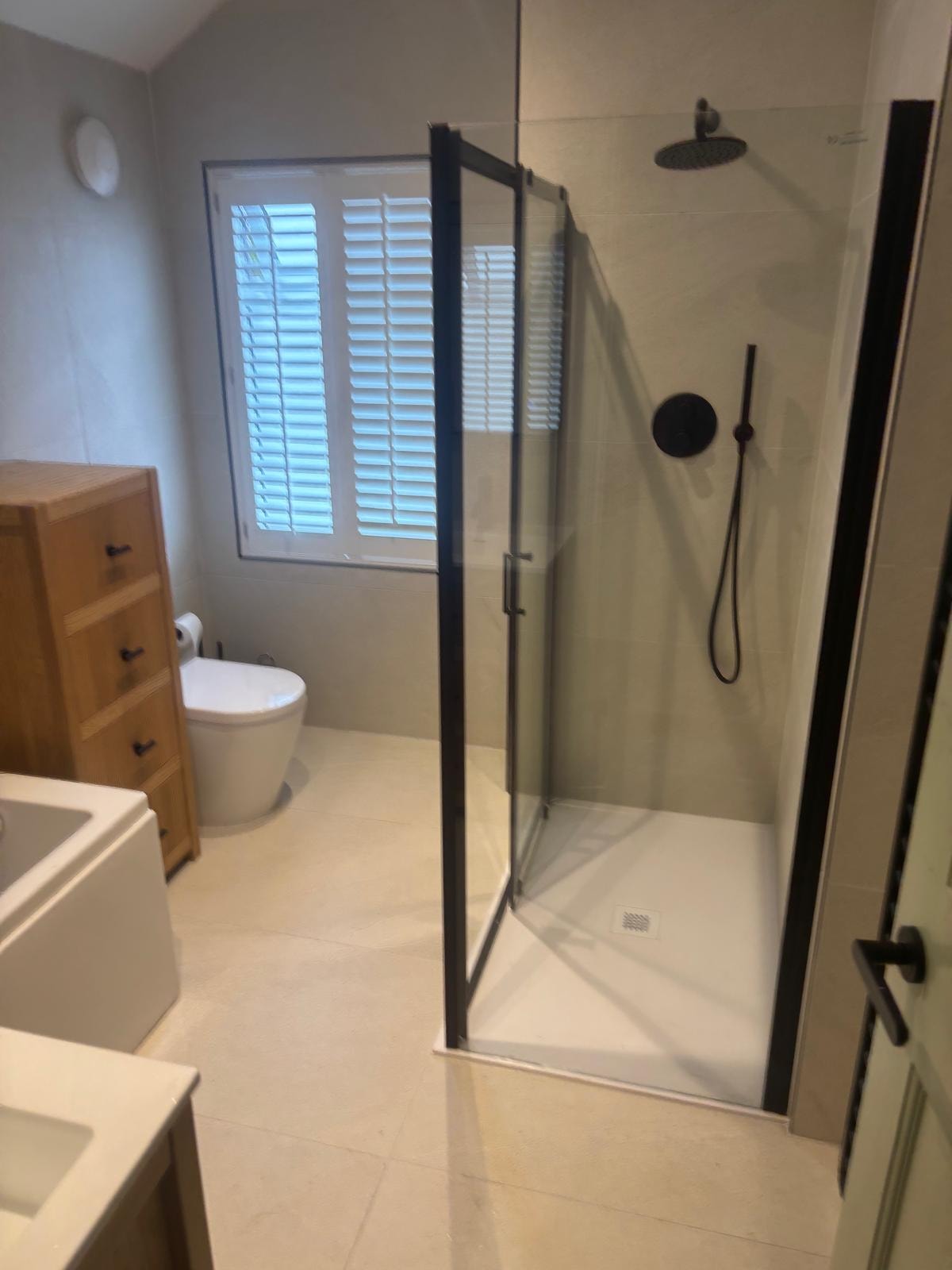 Modern shower enclosure with black frame and rain head — silicone sealed