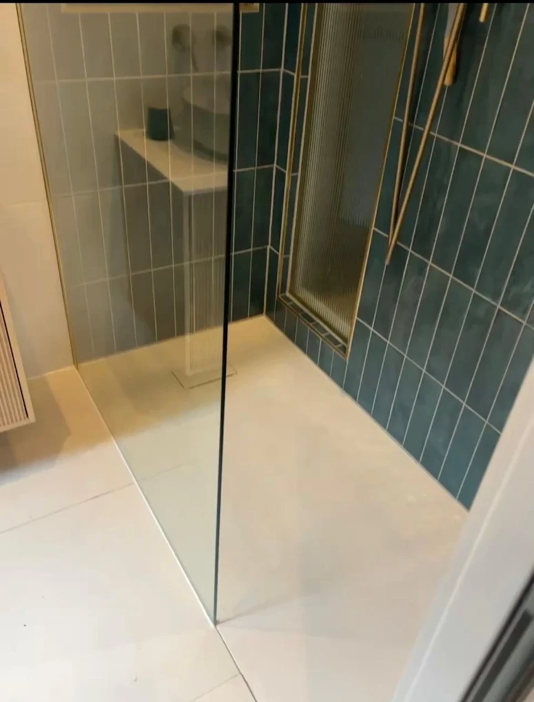 Teal subway tile shower enclosure with glass panel — silicone sealed